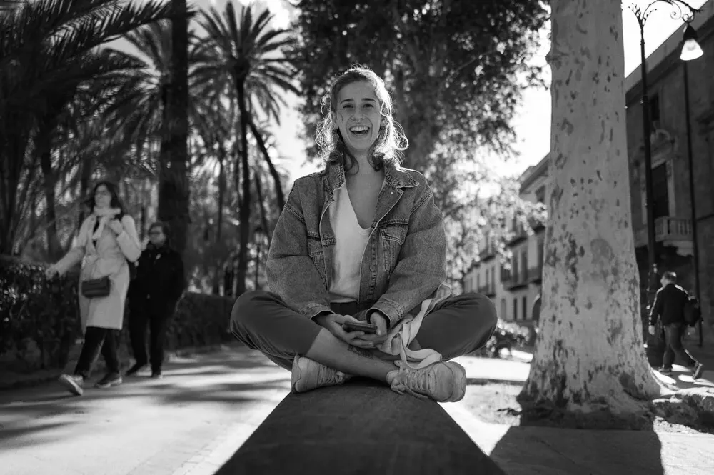 A woman sits cross-legged on a stone ledge