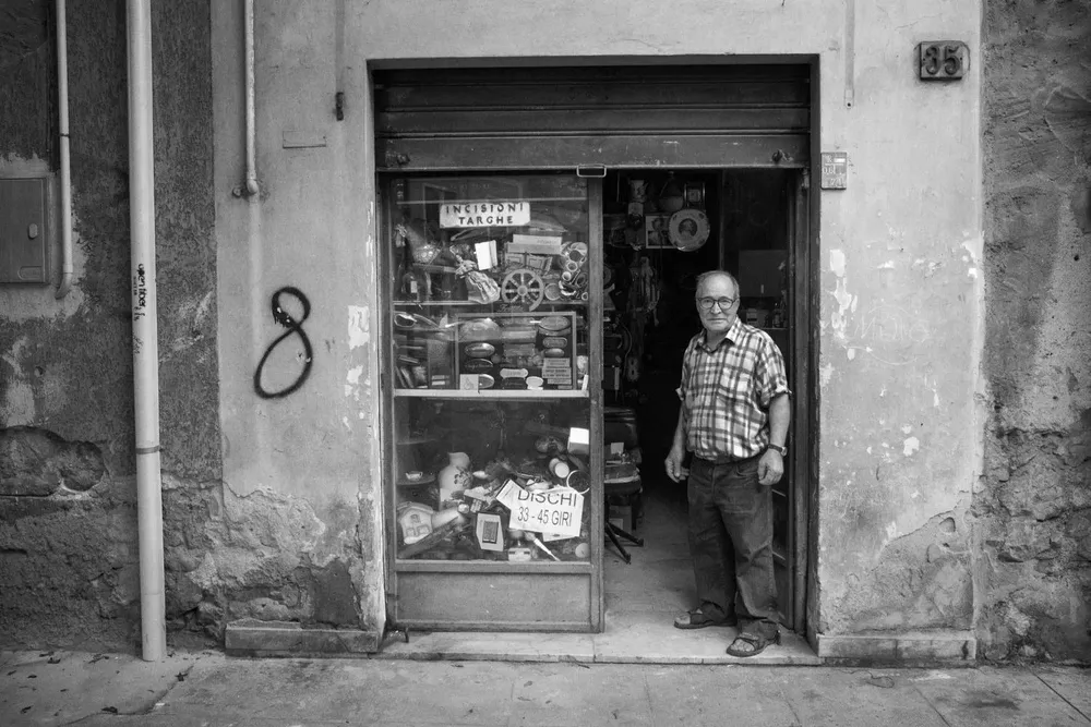 A man stands at a narrow shop entrance