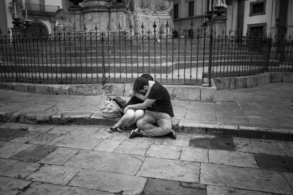 A person sits on a pavement with a dog