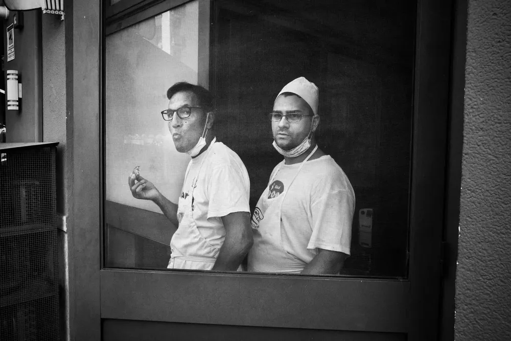 Two men stand behind a shop window
