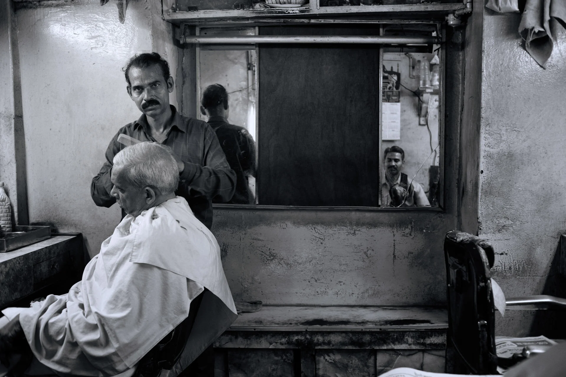 A barber cuts a seated customer's hair