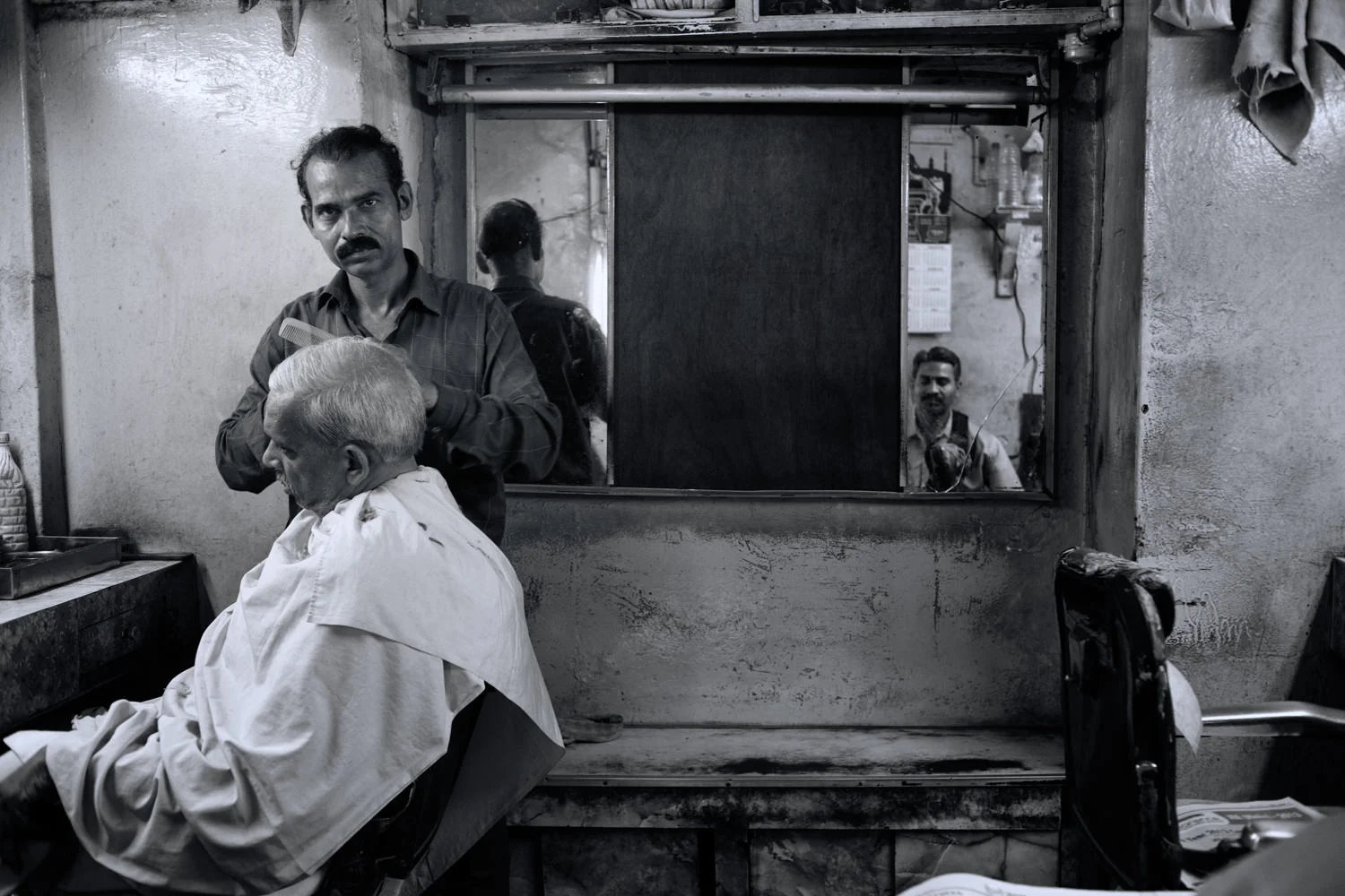 A barber cuts a seated customer's hair