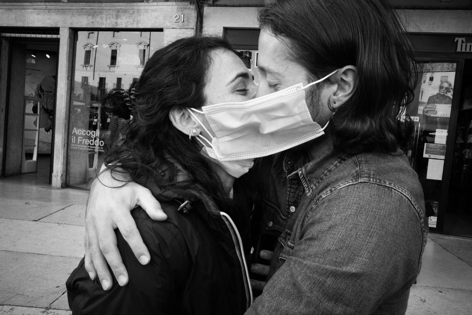 A couple embraces with a face mask between their faces