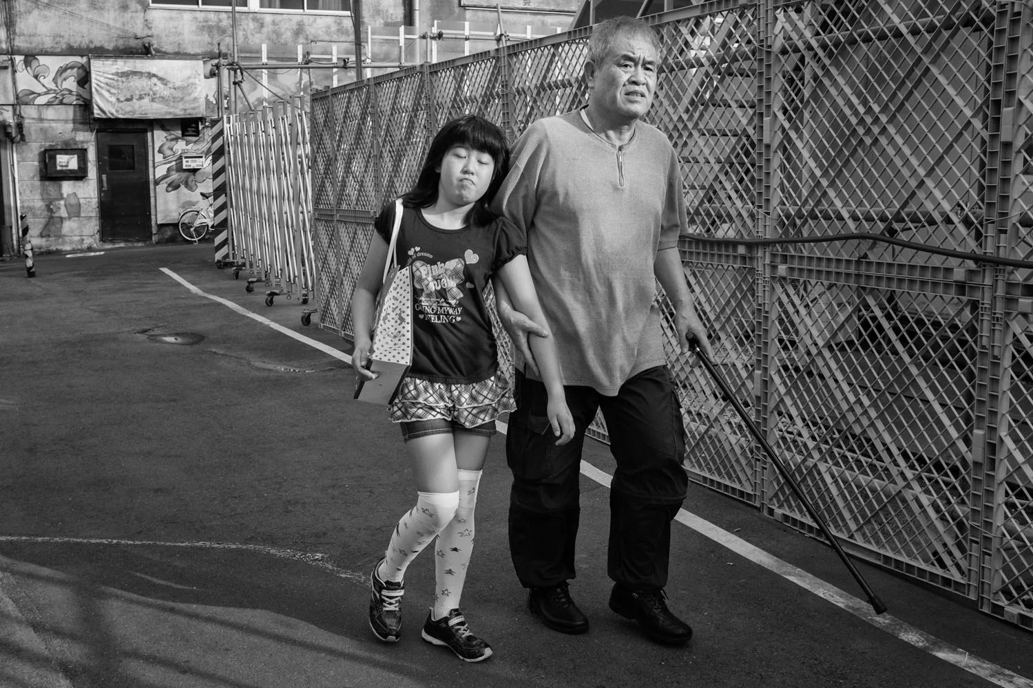 A couple walks beside a chain-link fence