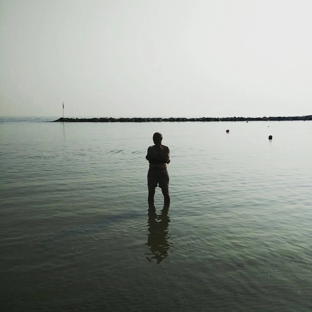A person stands in calm shallow seawater