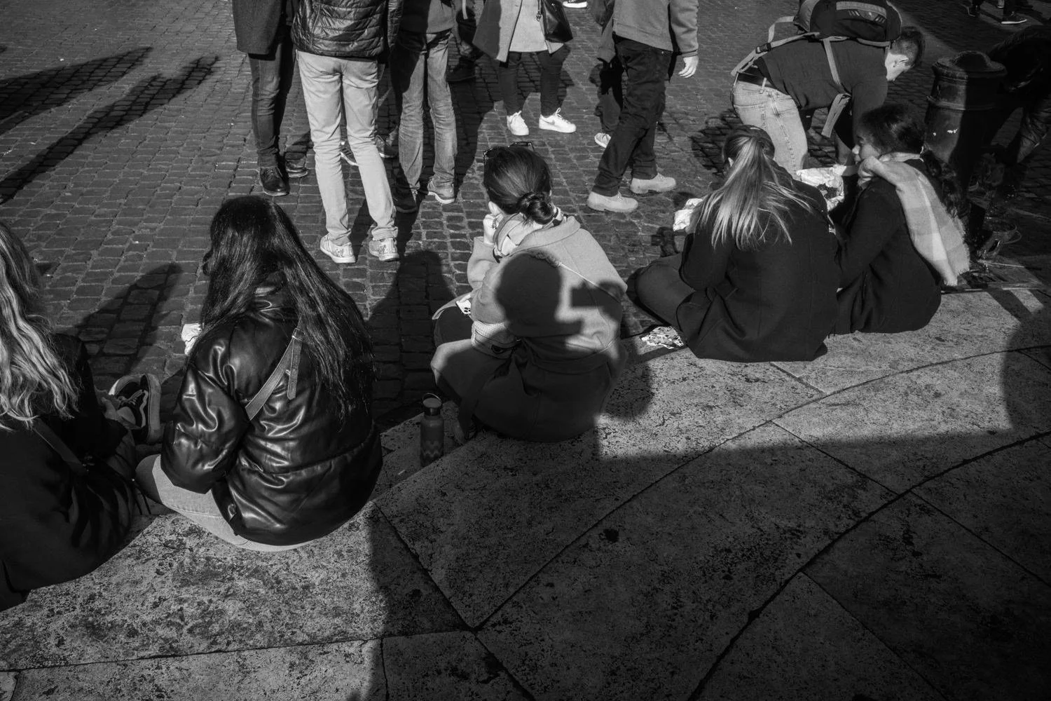 A group sits in a circle on stone paving