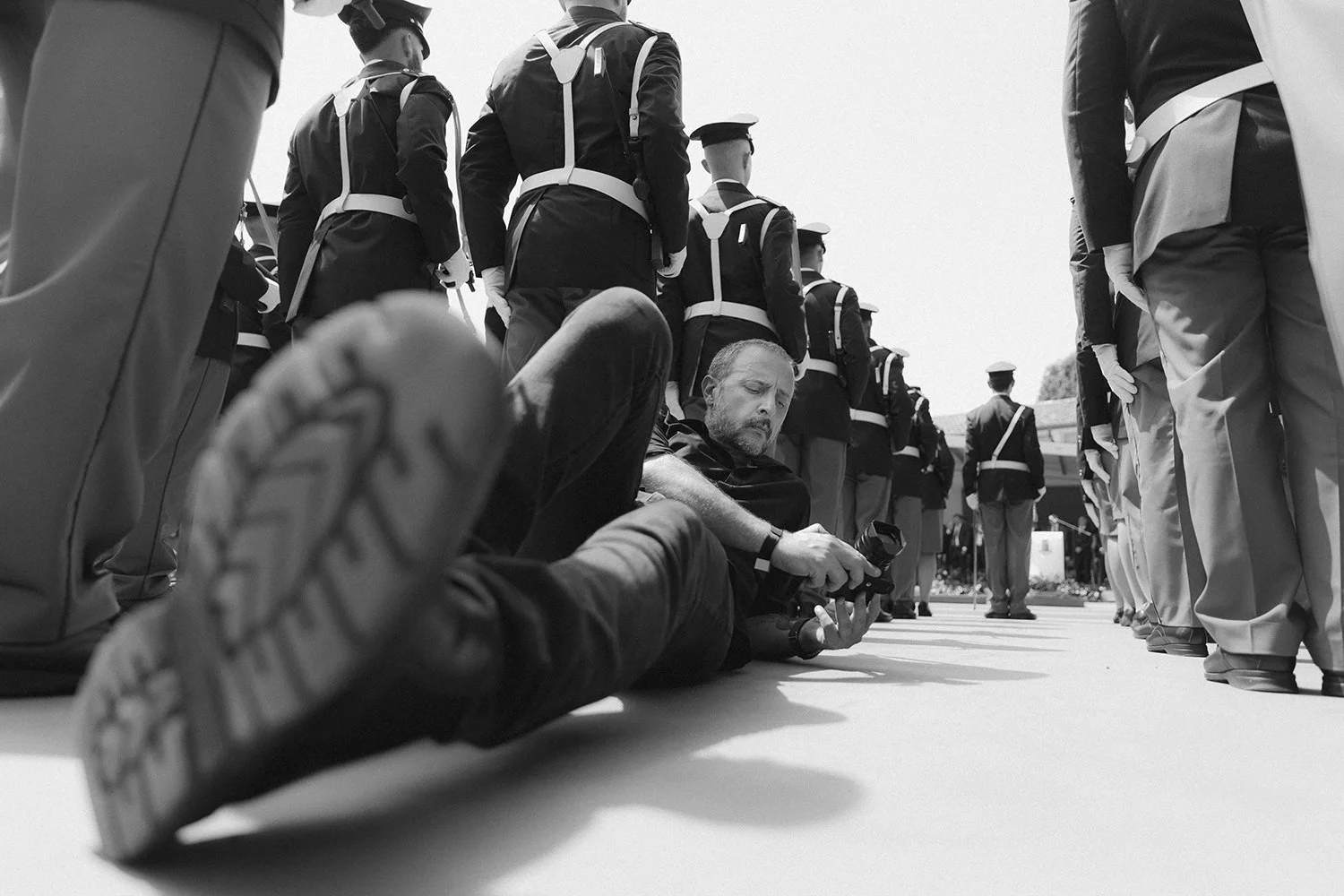 Low view of trainees exercising on the ground beside standing officers