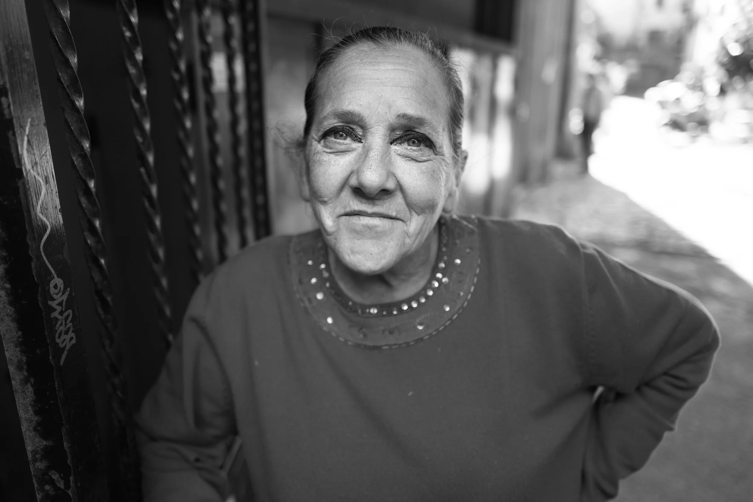An older woman smiles while standing in a street