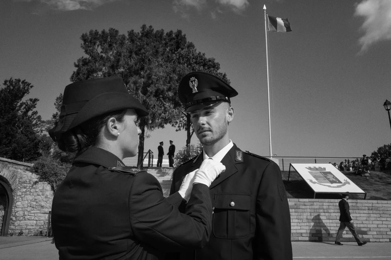 One uniformed officer adjusts another officer's collar