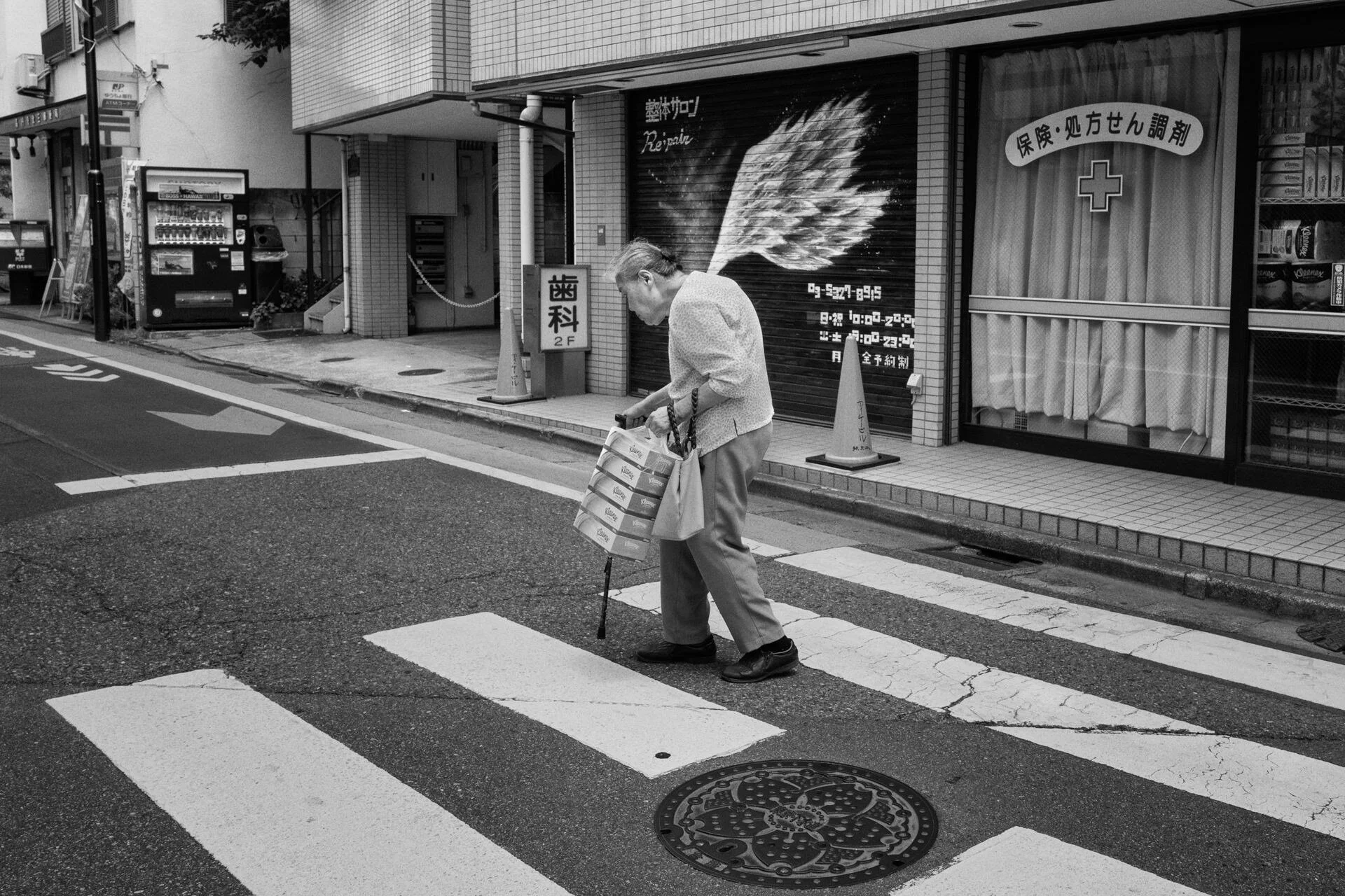 A pedestrian crosses a zebra crossing beneath a painted wing on a wall
