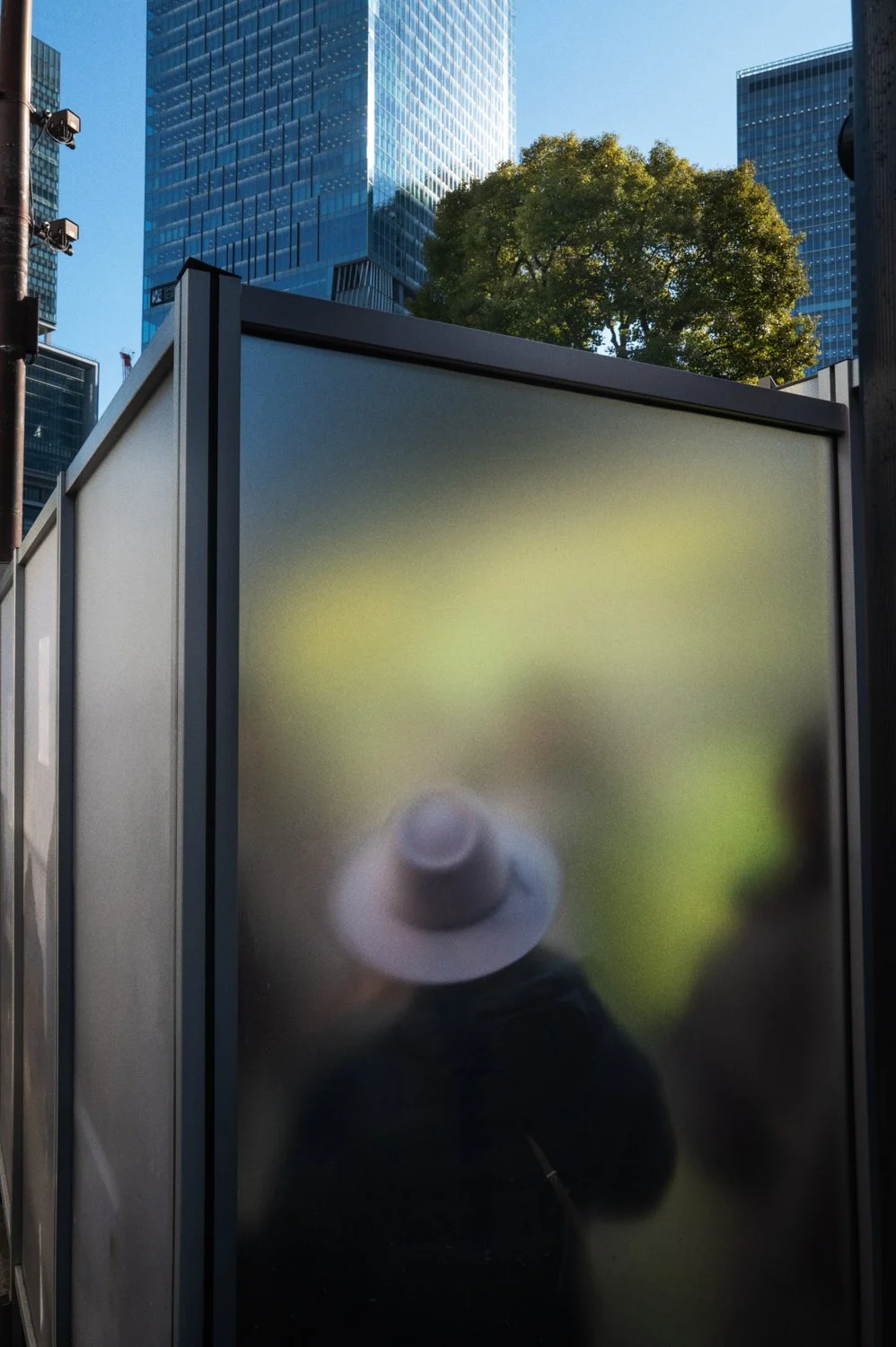 A person in a hat appears behind translucent glass