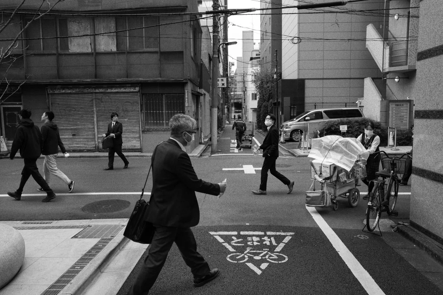 A person hurries across a narrow street in front of other pedestrians