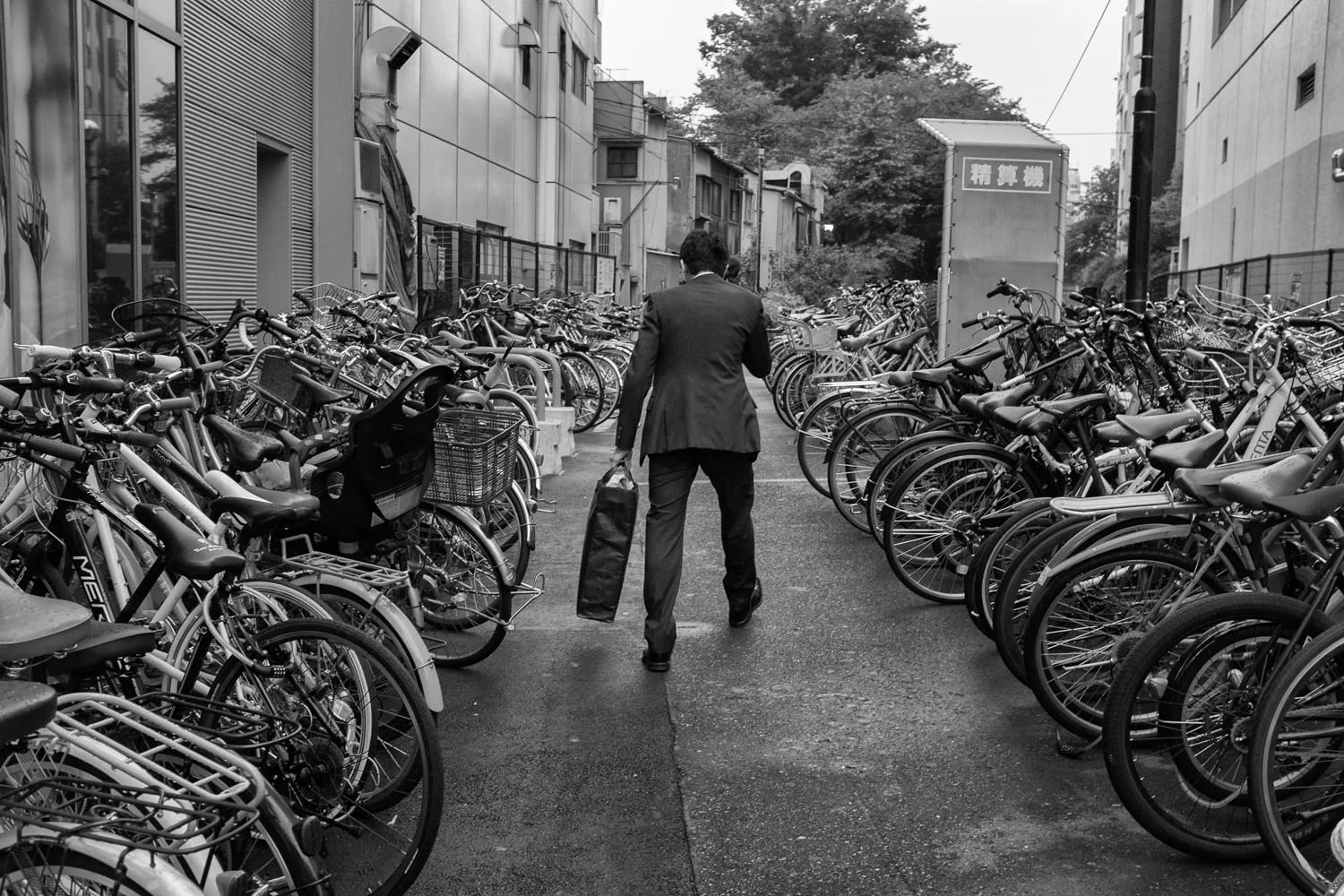 A person walks between tightly packed rows of bicycles