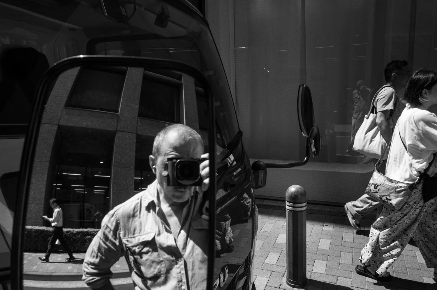 A photographer appears in a reflective street surface