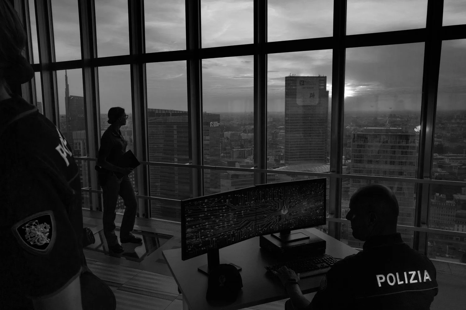 Police officers monitor screens in a glass-walled control room