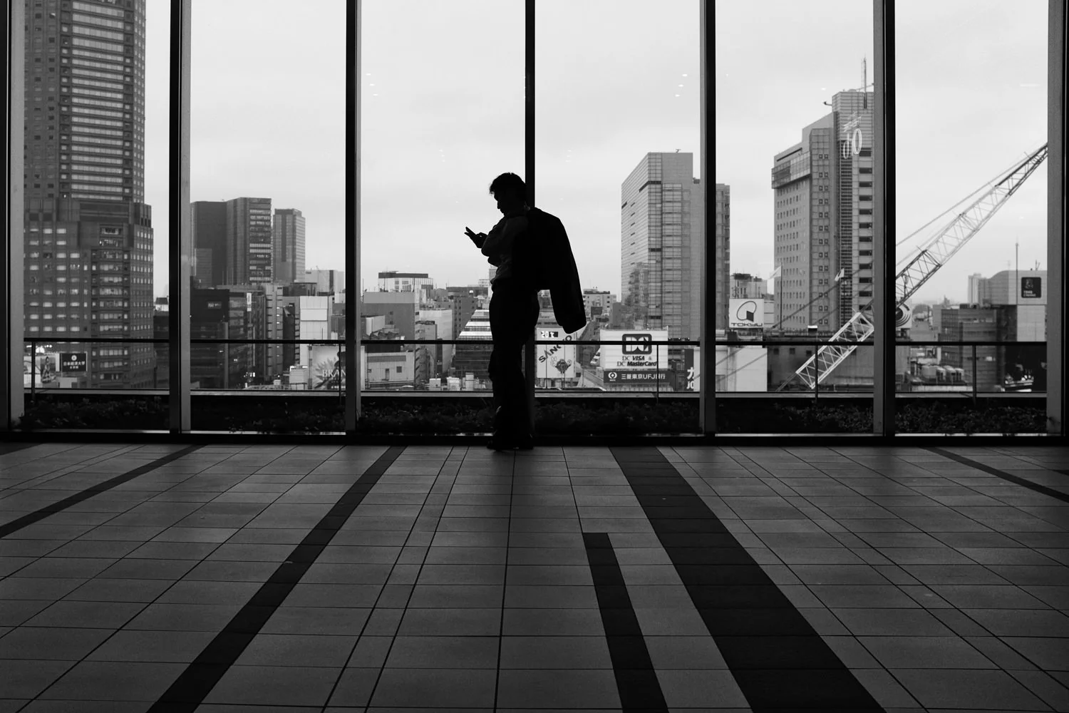 A silhouetted person stands before tall station windows