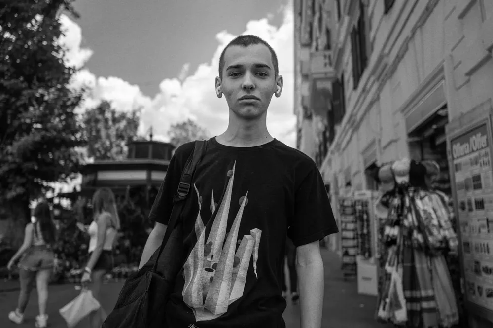 A young man poses on a shopping street in a black T-shirt
