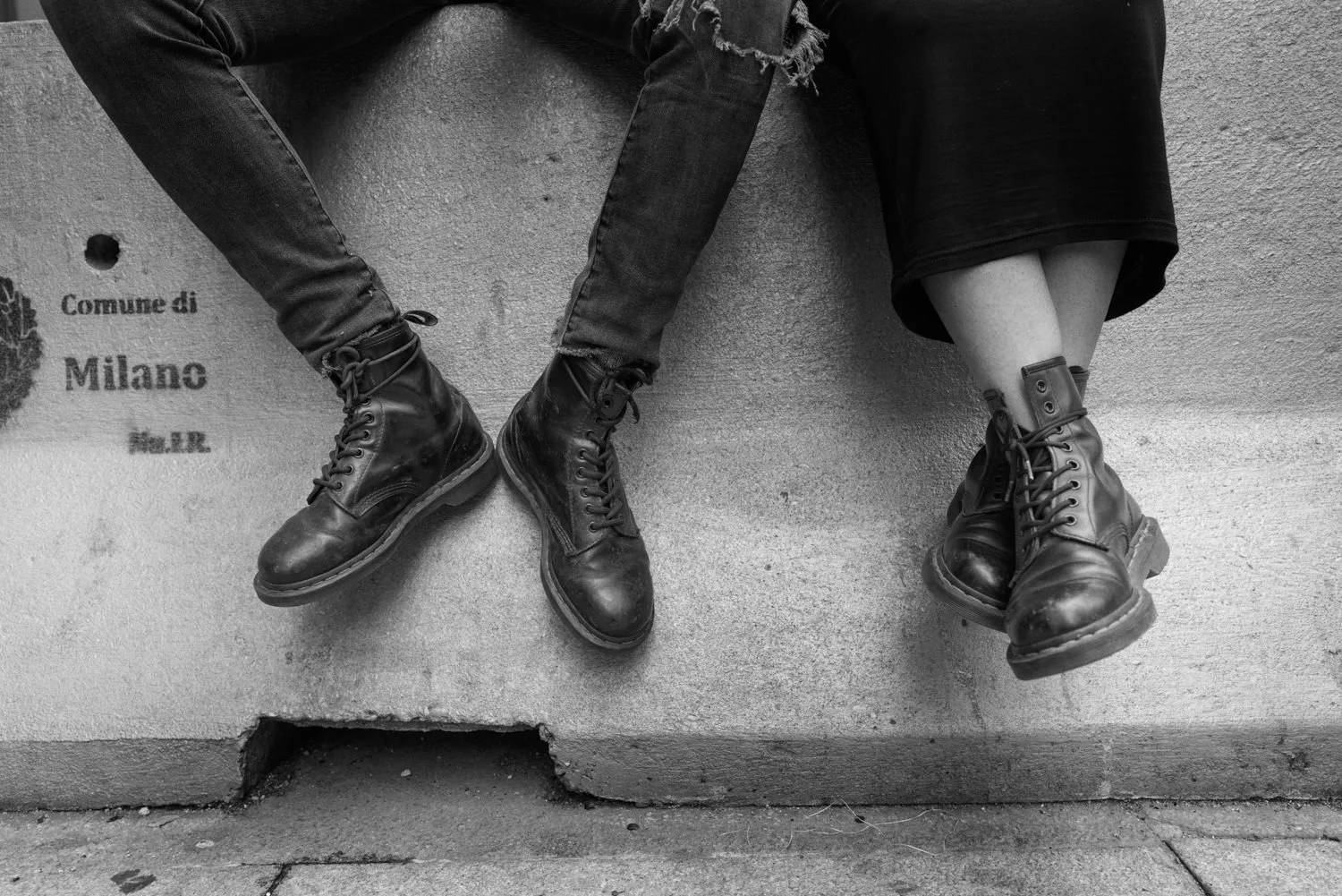 Two pairs of boots hang over the edge of a stone wall