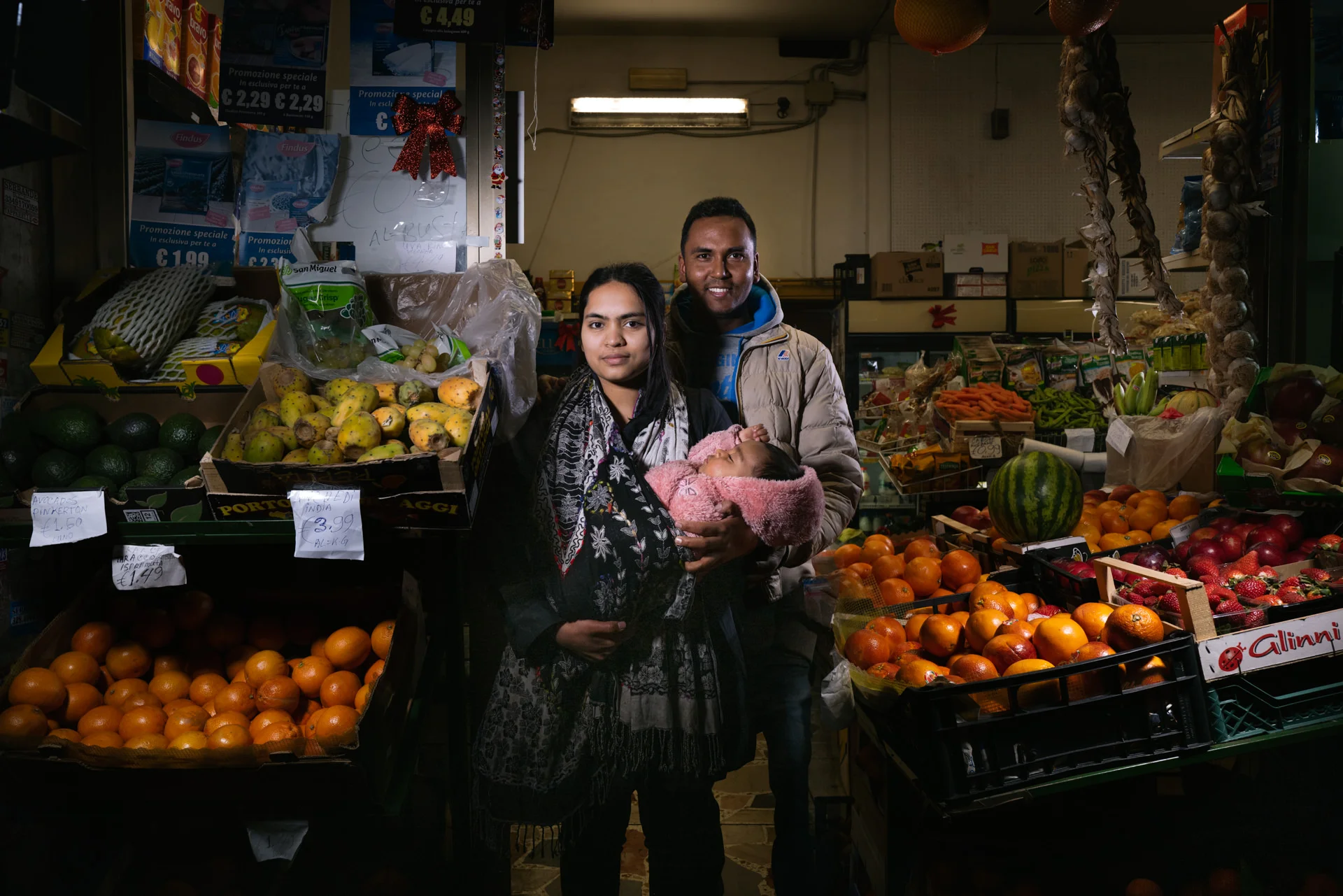Two people stand among fruit and vegetable displays