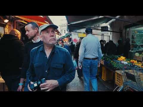Steve McCurry stands in a crowded market holding a camera