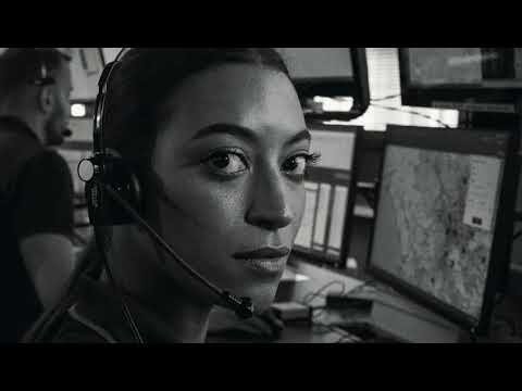 A police operator wearing a headset looks toward the camera