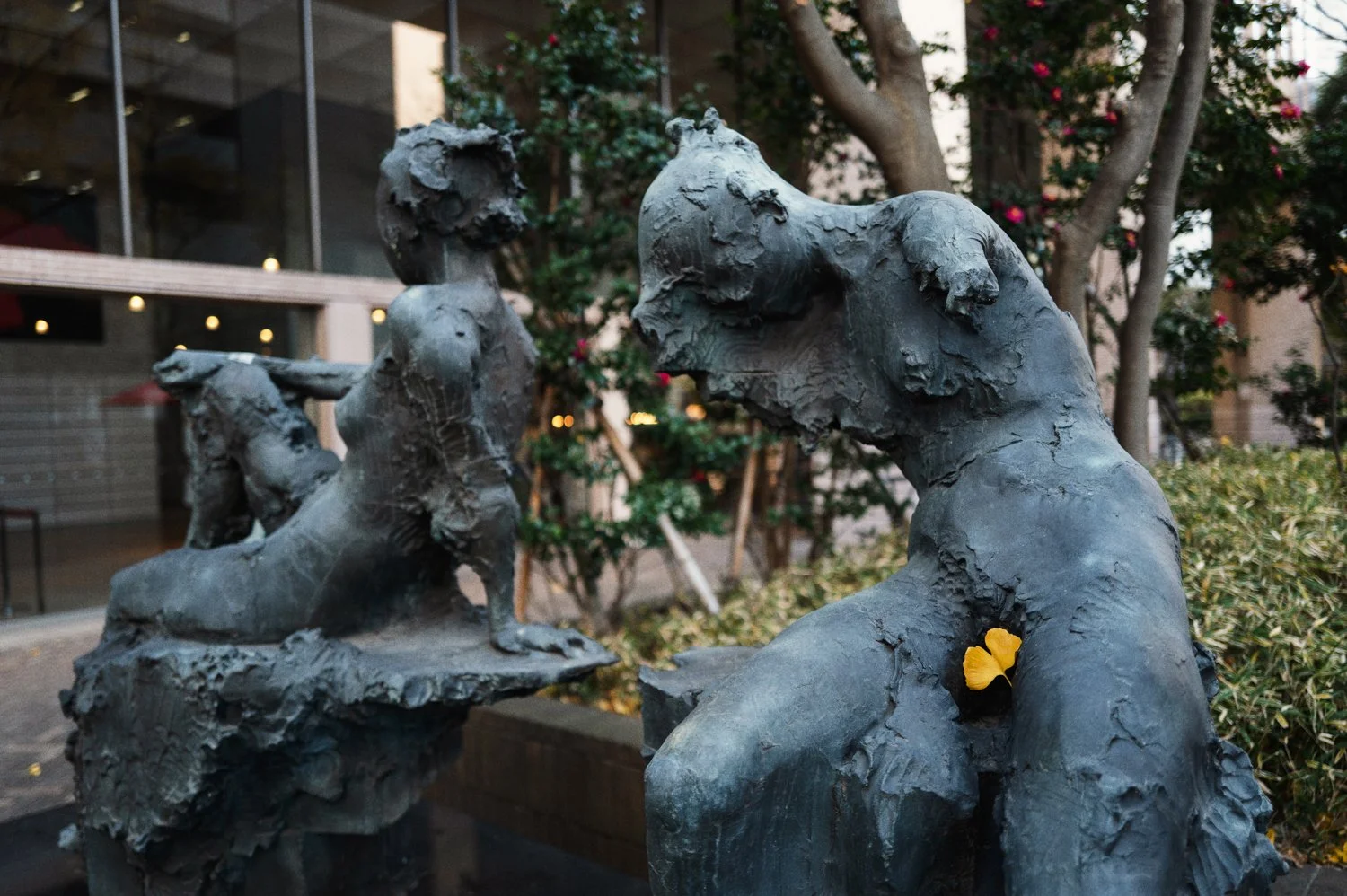 Weathered figurative sculptures stand among plants