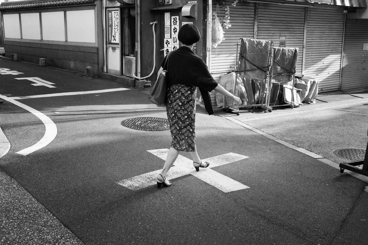 A woman crosses a painted road marking in a quiet street
