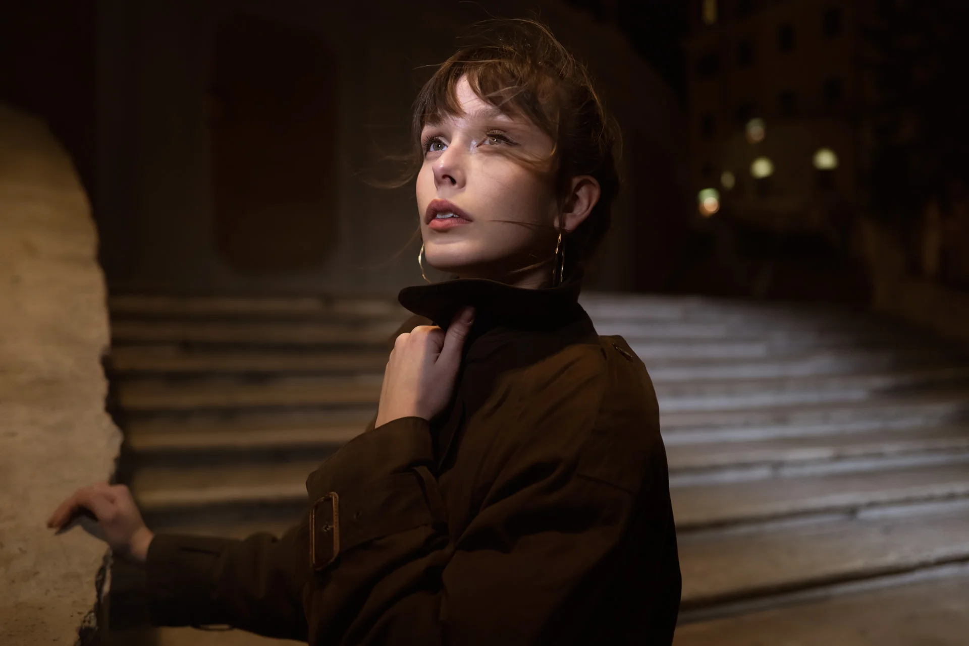 A woman looks upward on a softly lit night street